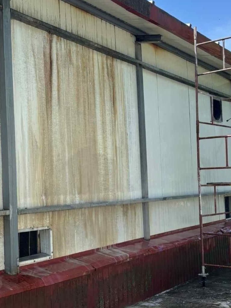 Zabrudzona elewacja budynku przed czyszczeniem w Białej Podlaskiej. Widoczne zacieki i zabrudzenia na panelach ściennych oraz częściowo metalowa konstrukcja.