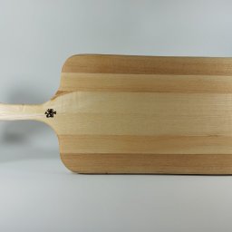 PA-TERA - Drewniana deska do krojenia z uchwytem w kształcie kości, wykonana z jasnego drewna z widocznym usłojeniem. Na desce widoczne logo producenta. Minimalistyczne tło.