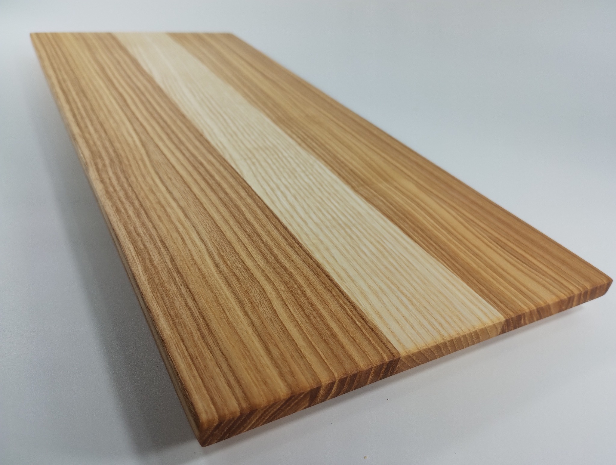 Drewniany blat z wyraźnym usłojeniem, ułożony ukośnie na białym tle. Widoczne połączenie jaśniejszych i ciemniejszych desek, tworzące unikalny wzór.