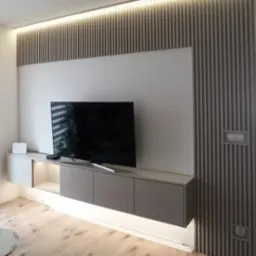 Nowoczesna szafka RTV z podświetleniem LED i dekoracyjną ścianką lamelową w salonie w Gliwicach. Minimalistyczny design, ciepłe oświetlenie.