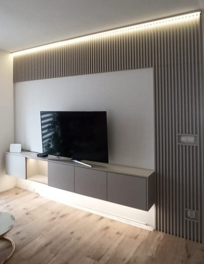 Nowoczesna szafka RTV z podświetleniem LED i dekoracyjną ścianką lamelową w salonie w Gliwicach. Minimalistyczny design, ciepłe oświetlenie.