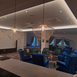 NJmalers - Ekskluzywne wnętrze z designerskimi lampami, komfortowymi fotelami i stołem do ping-ponga w tle. Oświetlenie LED podkreśla nowoczesny charakter pomieszczenia.