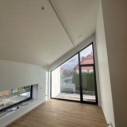 NJmalers - Jasne wnętrze po remoncie w Szczecinie: drewniana podłoga, białe ściany, okna z widokiem na zewnątrz. Minimalistyczny design i nowoczesne wykończenie.