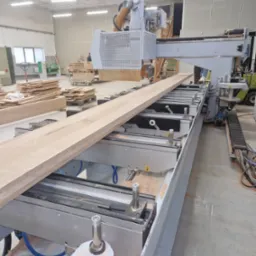 Obróbka deski na blat drewniany za pomocą frezarki CNC w warsztacie. Widoczne ślady obróbki i laserowe wyznaczenie wzoru.