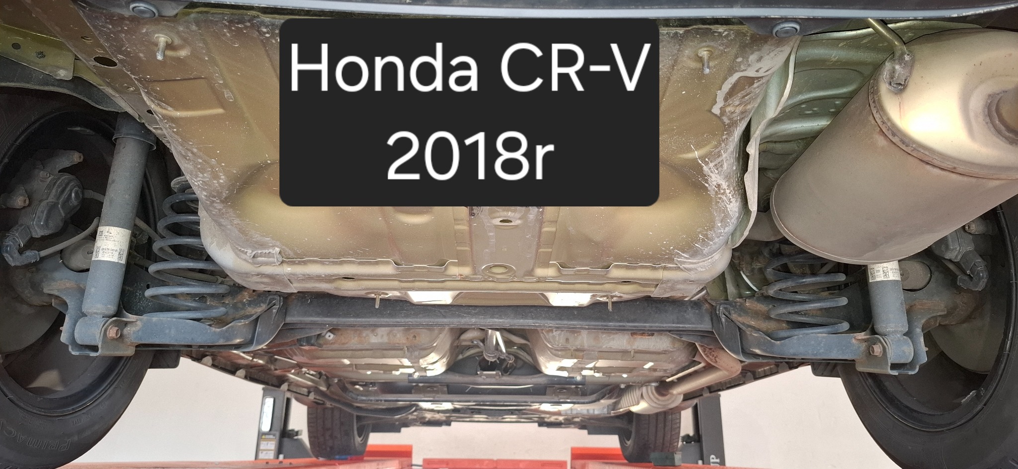 Podwozie Honda CR-V z 2018 roku po zabiegu konserwacji, widoczne elementy zawieszenia, układ wydechowy i zabezpieczona blacha podłogowa. Auto na podnośniku.