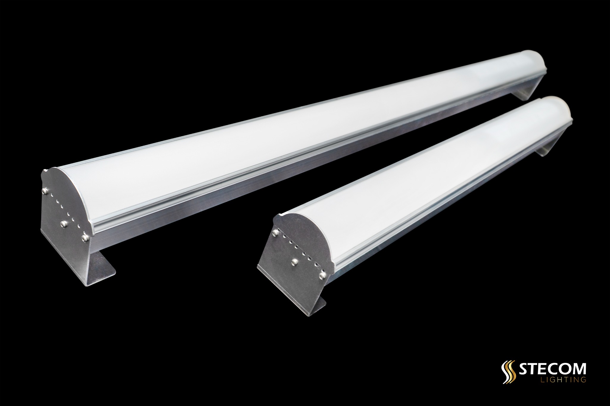 Dwie podłużne lampy LED z aluminiową obudową na czarnym tle, z widocznym logo Stecom Lighting w prawym dolnym rogu. Prezentacja produktu oświetleniowego.