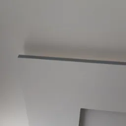 Nowoczesny sufit podwieszany z oświetleniem LED, wykończony gładzią w odcieniach bieli i szarości. Minimalistyczny design, kątowe ujęcie z dołu.