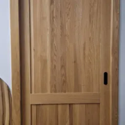 Dębowa, wewnętrzna stolarka drzwiowa z czarnym, minimalistycznym uchwytem, prezentująca naturalne usłojenie drewna i precyzję wykonania.
