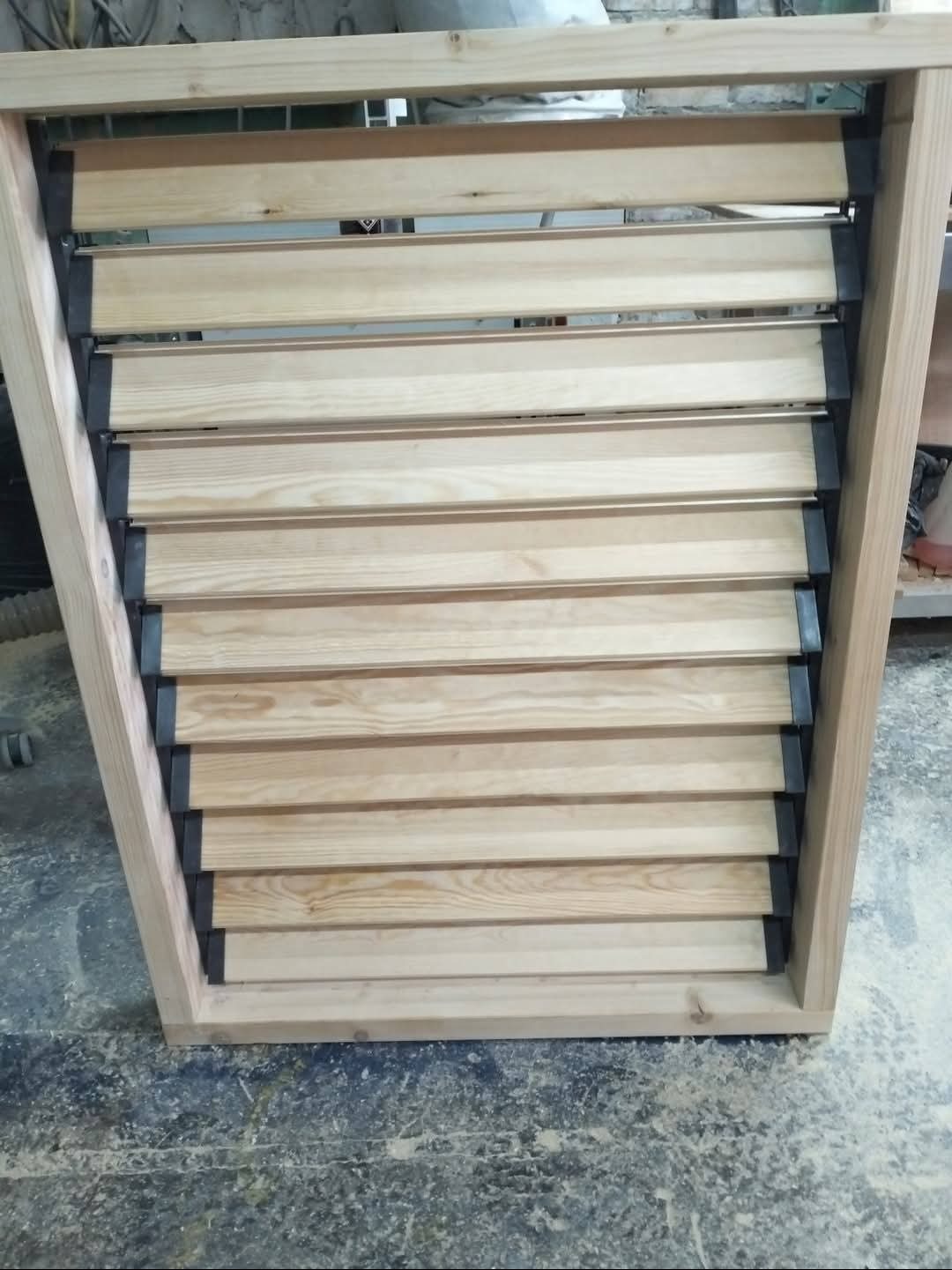 Drewniana konstrukcja z lamelami, prawdopodobnie fragment zabudowy balkonu lub element dekoracyjny, surowe drewno, widoczne detale montażowe.