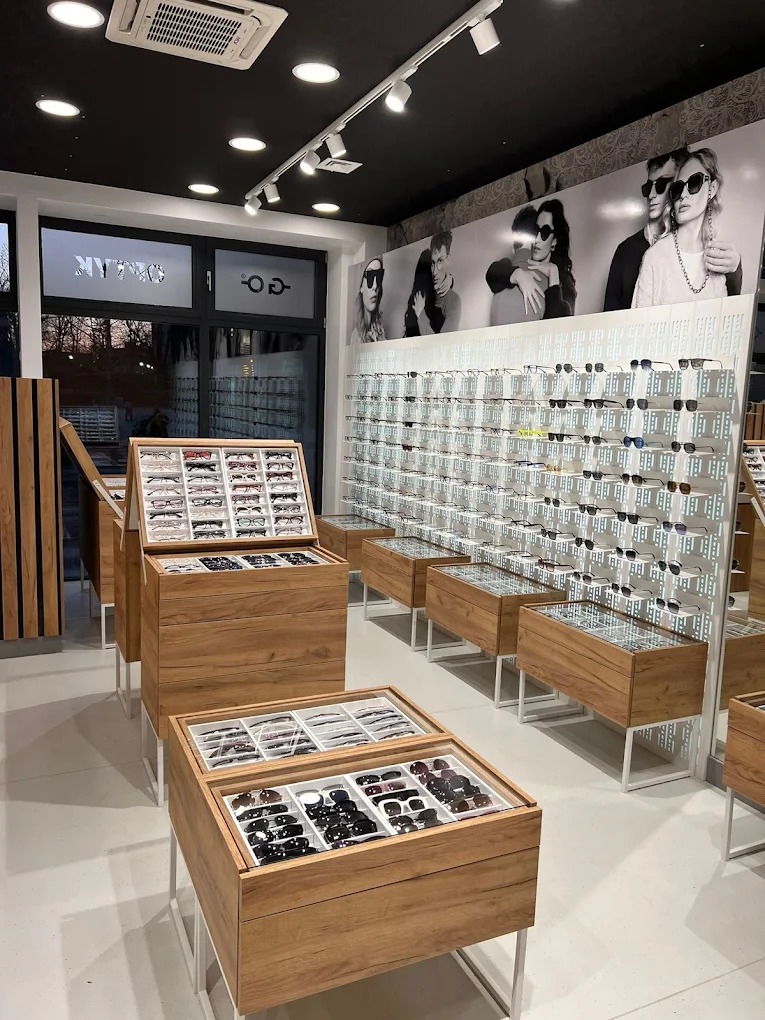 Salon optyczny w Będzinie prezentuje bogaty wybór okularów korekcyjnych i przeciwsłonecznych na drewnianych ekspozytorach i ścianie z perforacją.