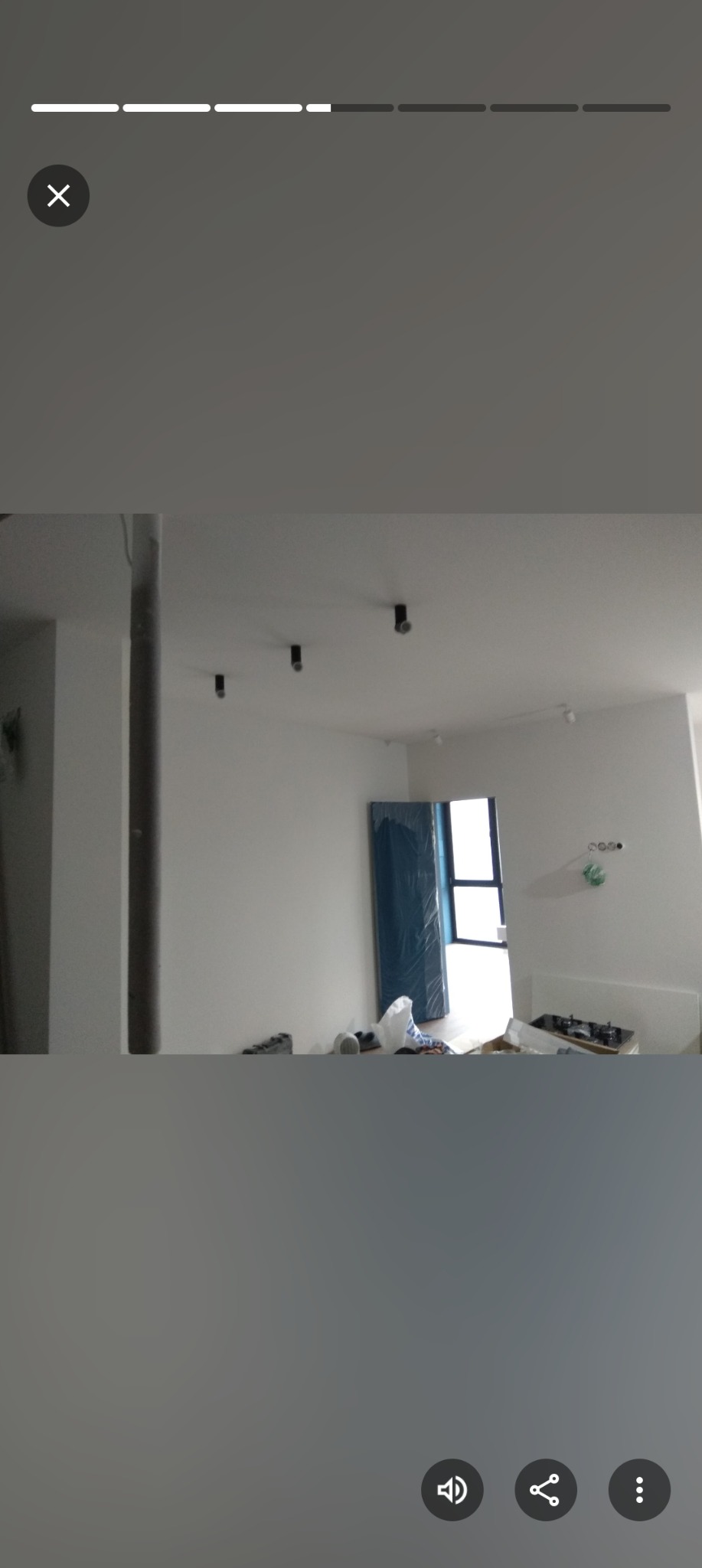 Wnętrze w trakcie remontu: białe ściany, zamontowane czarne reflektory sufitowe, drzwi zabezpieczone folią, widoczne narzędzia i materiały budowlane.