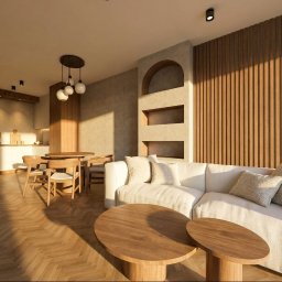 Joanna Brzezina - Nowoczesny salon z aneksem kuchennym, drewnianą ścianą lamelową i wnęką z łukiem. Jasna sofa, okrągłe stoliki kawowe, jodełkowy parkiet. W tle jadalnia. Ciepłe, naturalne światło.