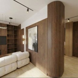 Joanna Brzezina - Nowoczesny salon z ciemnymi panelami drewnianymi, zaokrągloną ścianą, białym modułowym narożnikiem, kominkiem, dużym zielonym kwiatem i minimalistycznym oświetleniem szynowym.