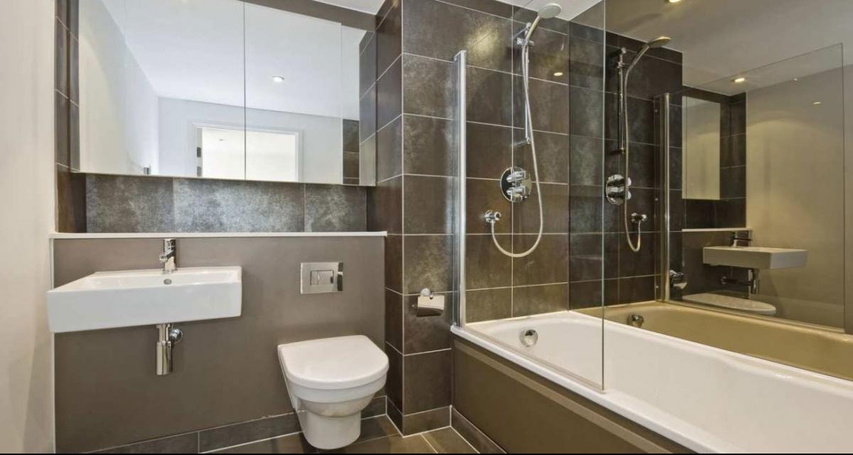 Nowoczesna łazienka z brązowymi płytkami, białą ceramiką i szklaną kabiną prysznicową. Minimalistyczny design, eleganckie wykończenie.