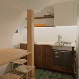 KIKU STUDIO Małgorzata Kudlik - Wnętrze kuchni w skandynawskim stylu z drewnianym stołem, hokerami i zabudową kuchenną. W tle okno i półki z dekoracjami. Ujęcie z perspektywy.