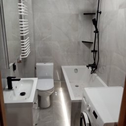 SEBA SERWIS DOMOWY Firma Remontowo-Budowlana Tomasik Sebastian - Nowoczesna łazienka po remoncie: szare płytki, biała armatura, czarna bateria i deszczownica. Zwraca uwagę grzejnik drabinkowy i oświetlenie LED pod wanną.