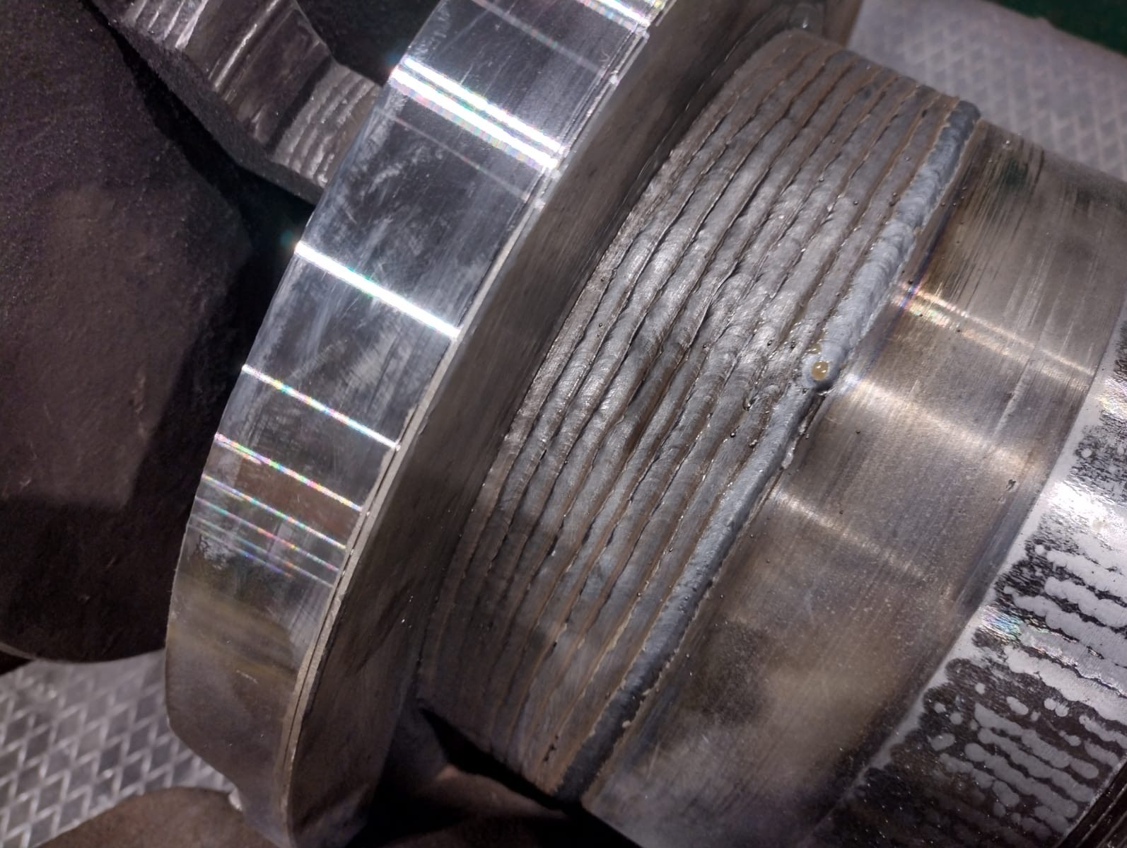 Metalowy element po obróbce z widocznymi śladami spawania, ukazujący detale i jakość wykonanej pracy. Widoczne liczne spoiny.