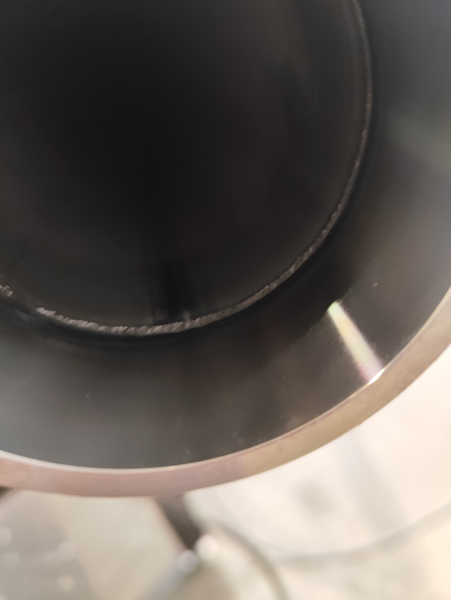 Wnętrze metalowej rury ze spoiną, ukazujące precyzję wykonania. Widoczne detale łączenia i gładka powierzchnia metalu.