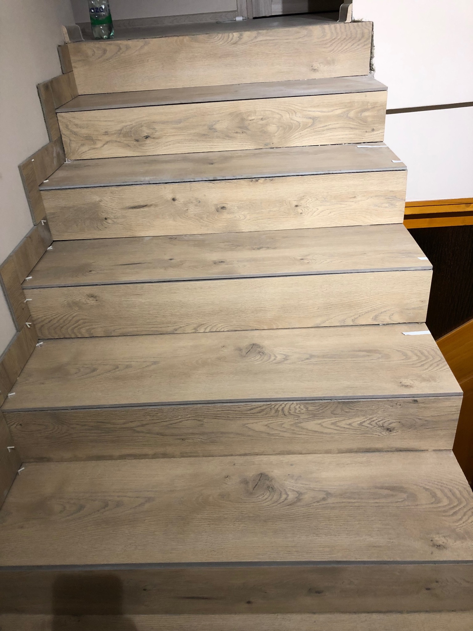 Wykończone schody z drewnopodobnych paneli w Podegrodziu. Widoczne detale montażu i estetyczne wykończenie stopni. Jasne, naturalne odcienie drewna.