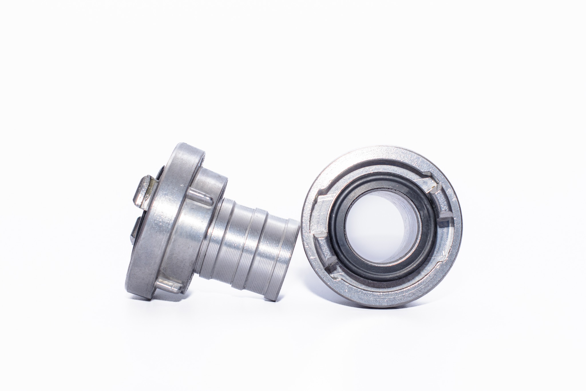 Dwa srebrne złącza metalowe na białym tle, jedno z gwintowanym wlotem, drugie z uszczelką, precyzyjnie obrobione, widoczne ślady obróbki.