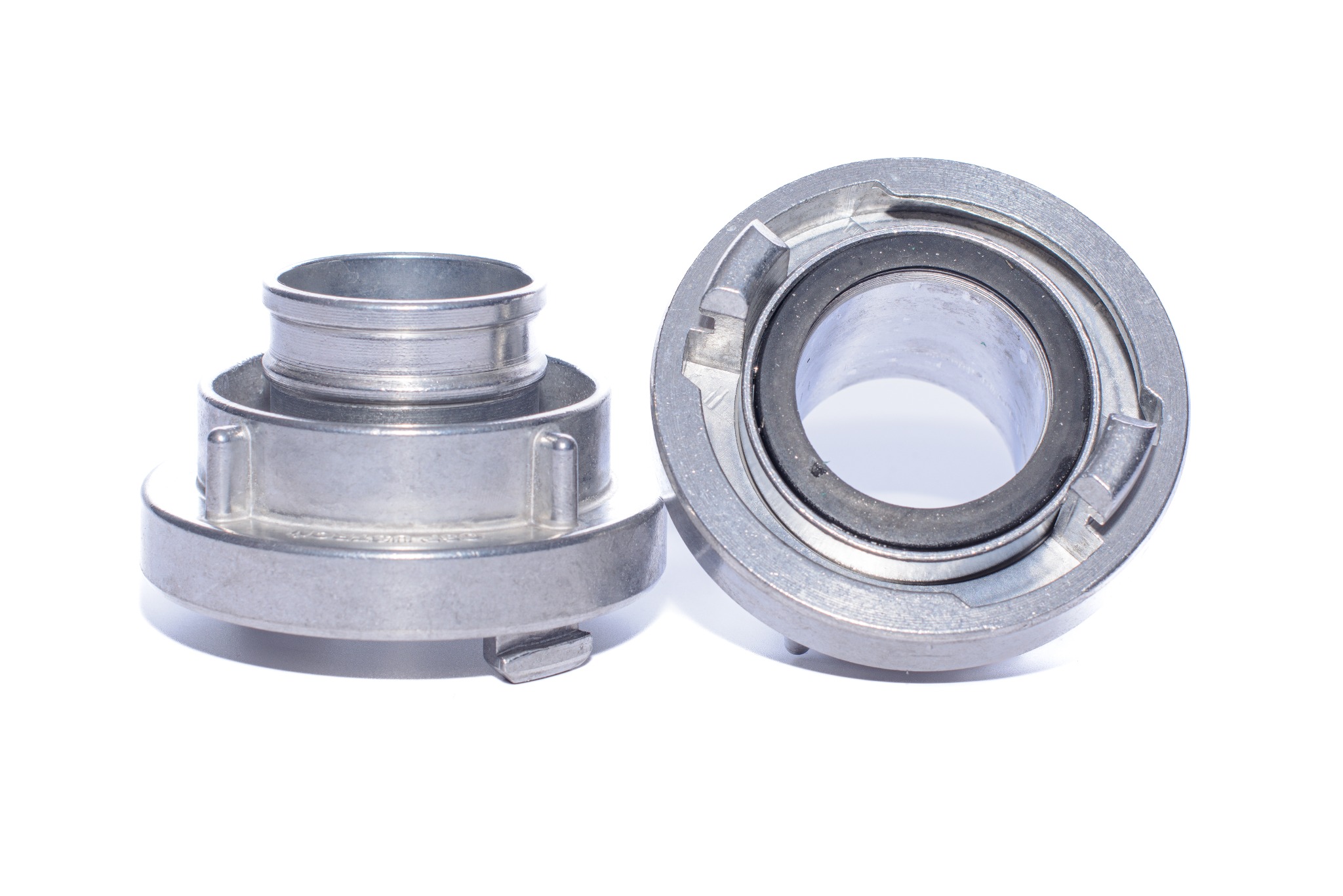 Dwie złączki strażackie ze srebrnego metalu na białym tle, z widocznymi detalami gwintów i uszczelki, ukazane w jasnym oświetleniu.