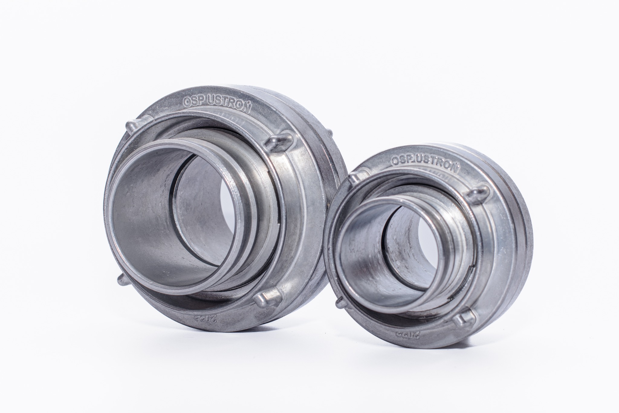 Dwa metalowe złącza rurowe OSP USTRON, różnej wielkości, na białym tle. Widoczne detale obróbki i numer seryjny na obudowie.