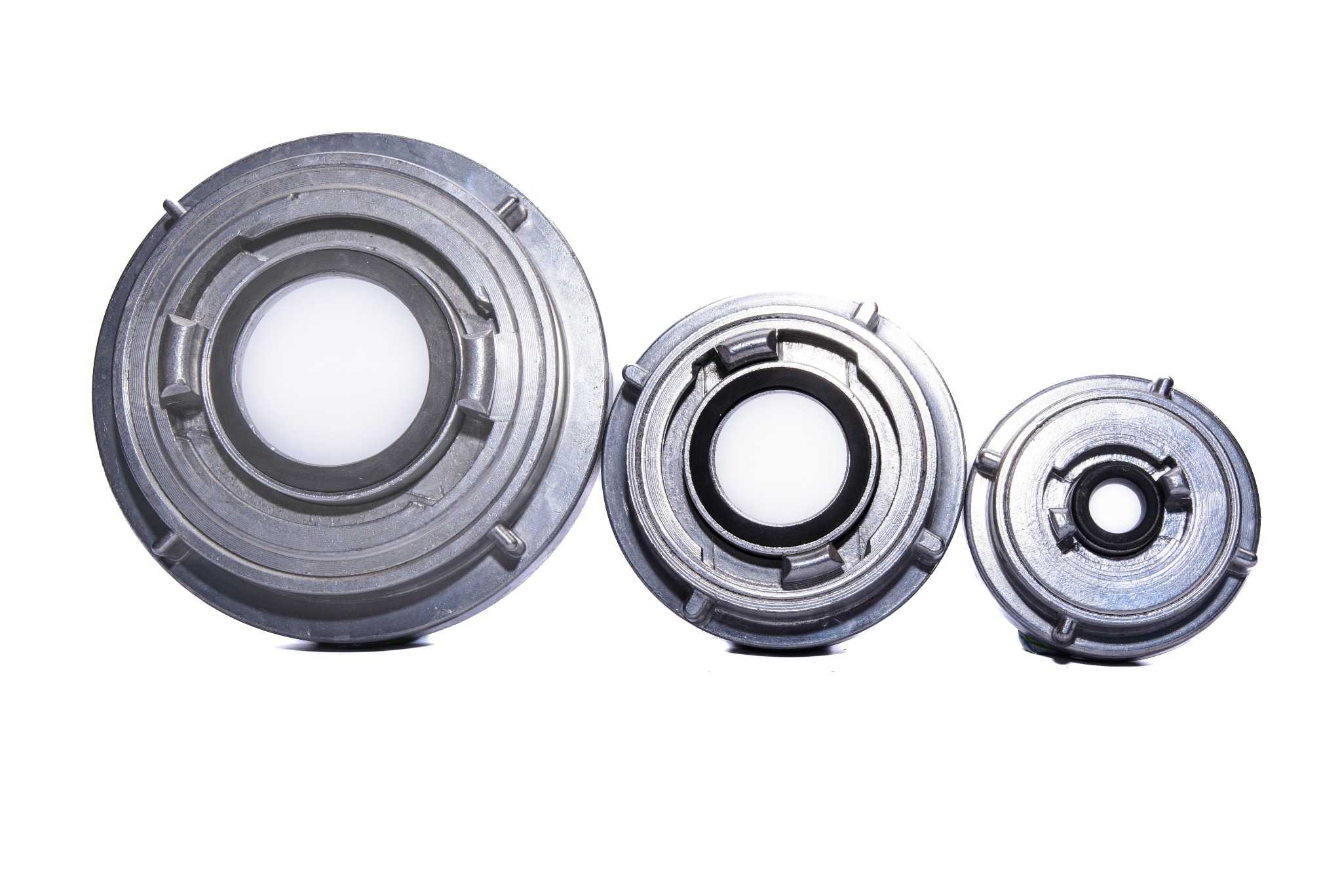 Trzy metalowe, okrągłe elementy z otworami w środku, ułożone obok siebie, różniące się wielkością i detalami konstrukcyjnymi, na białym tle. Widoczne ślady obróbki.