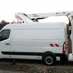 Biały furgon z podnośnikiem koszowym France Elevateur 152TPF zaparkowany na zewnątrz, widok z boku, z wysuniętym ramieniem i koszem. Stabilizatory wysunięte.