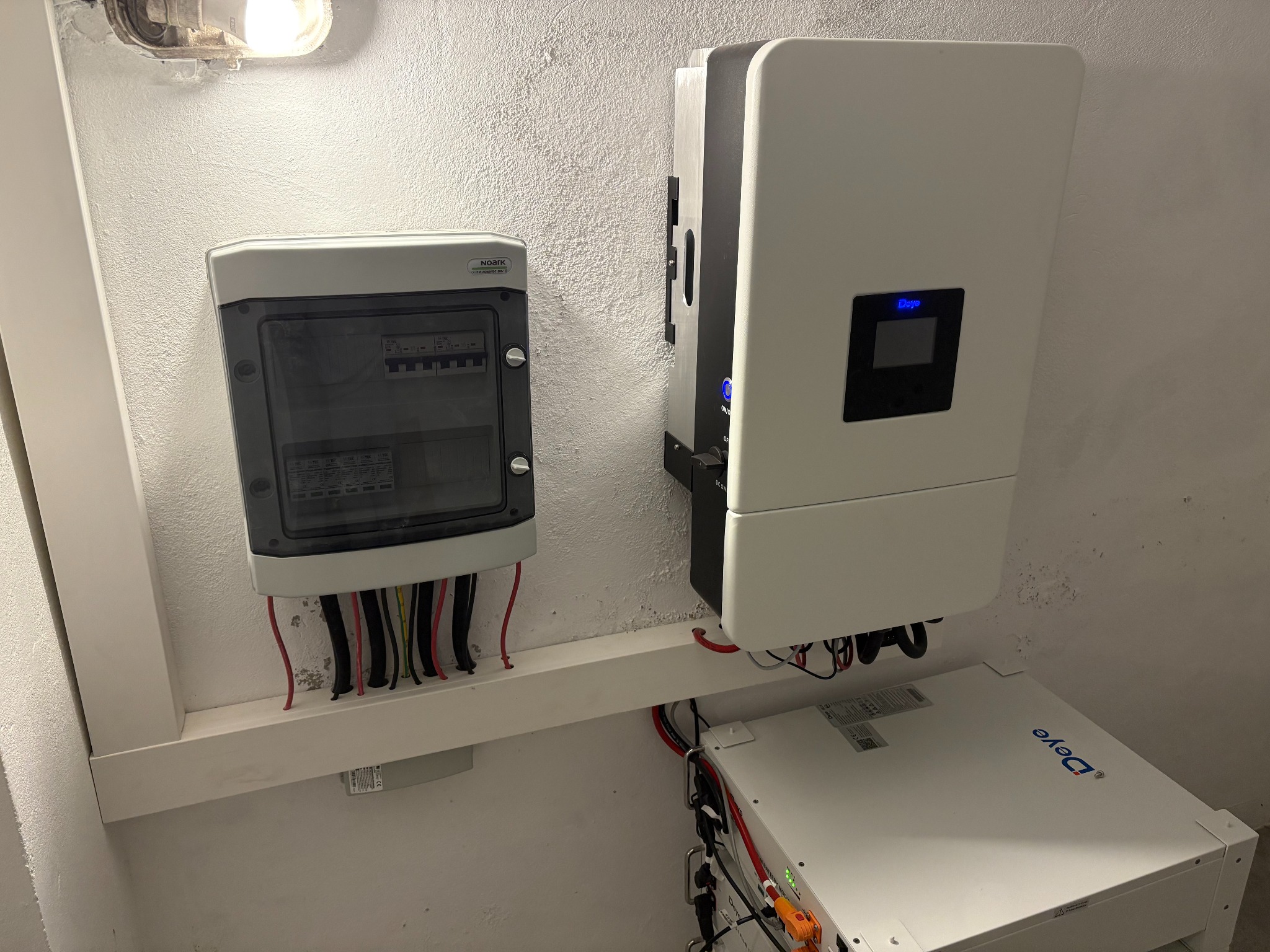 Kompletna instalacja fotowoltaiczna w pomieszczeniu: rozdzielnica Noark, inwerter Deye i magazyn energii Deye. Widoczne okablowanie i elementy montażowe.