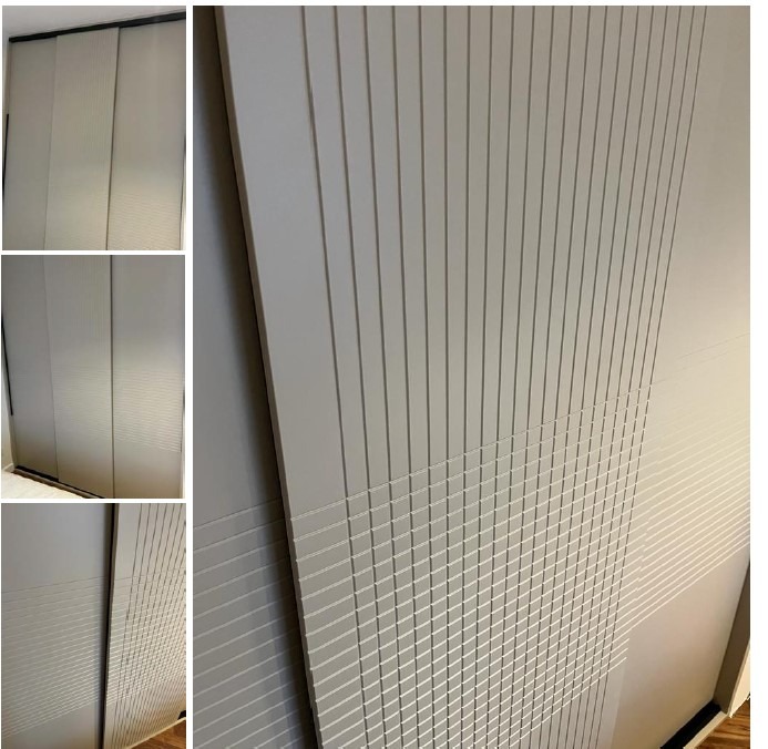 Nowoczesna szafa przesuwna z szarymi drzwiami. Dekoracyjne frezy tworzą pionowy wzór, przechodzący w geometryczną siatkę w dolnej części.