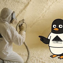 Thermoclad - Pracownik w kombinezonie spryskuje pianą PUR ścianę, obok pingwin w koszulce z logo firmy. Nietypowe ujęcie procesu ocieplania pianką.