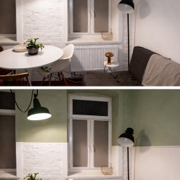 MajsterKolor - Jasne wnętrze po odświeżeniu: białe ściany z cegły, okno z grzejnikiem, okrągły stół z rośliną, sofa i lampy. Minimalistyczny design z akcentami kolorystycznymi.