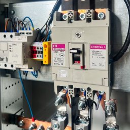 DP spółka z o.o. spółka kom. - Wnętrze rozdzielnicy elektrycznej z głównym wyłącznikiem ETI ED2S 250/3 w pozycji 'ON', modułem ZAMEL APM-20, miedzianymi szynami prądowymi i profesjonalnym okablowaniem faz L1, L2, L3.