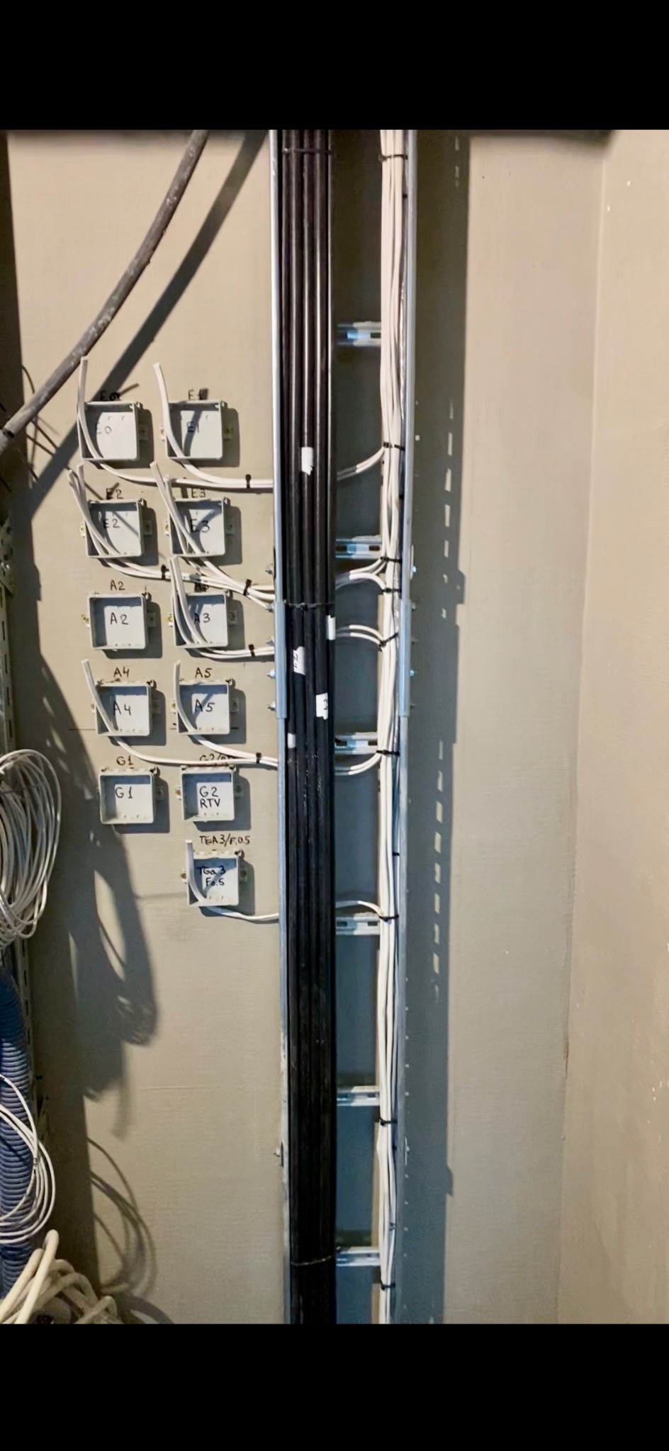 Instalacja kabli w korytkach i puszkach montażowych z oznaczeniami, widoczne przewody w kolorze białym i czarnym. Estetyczne ułożenie przewodów.