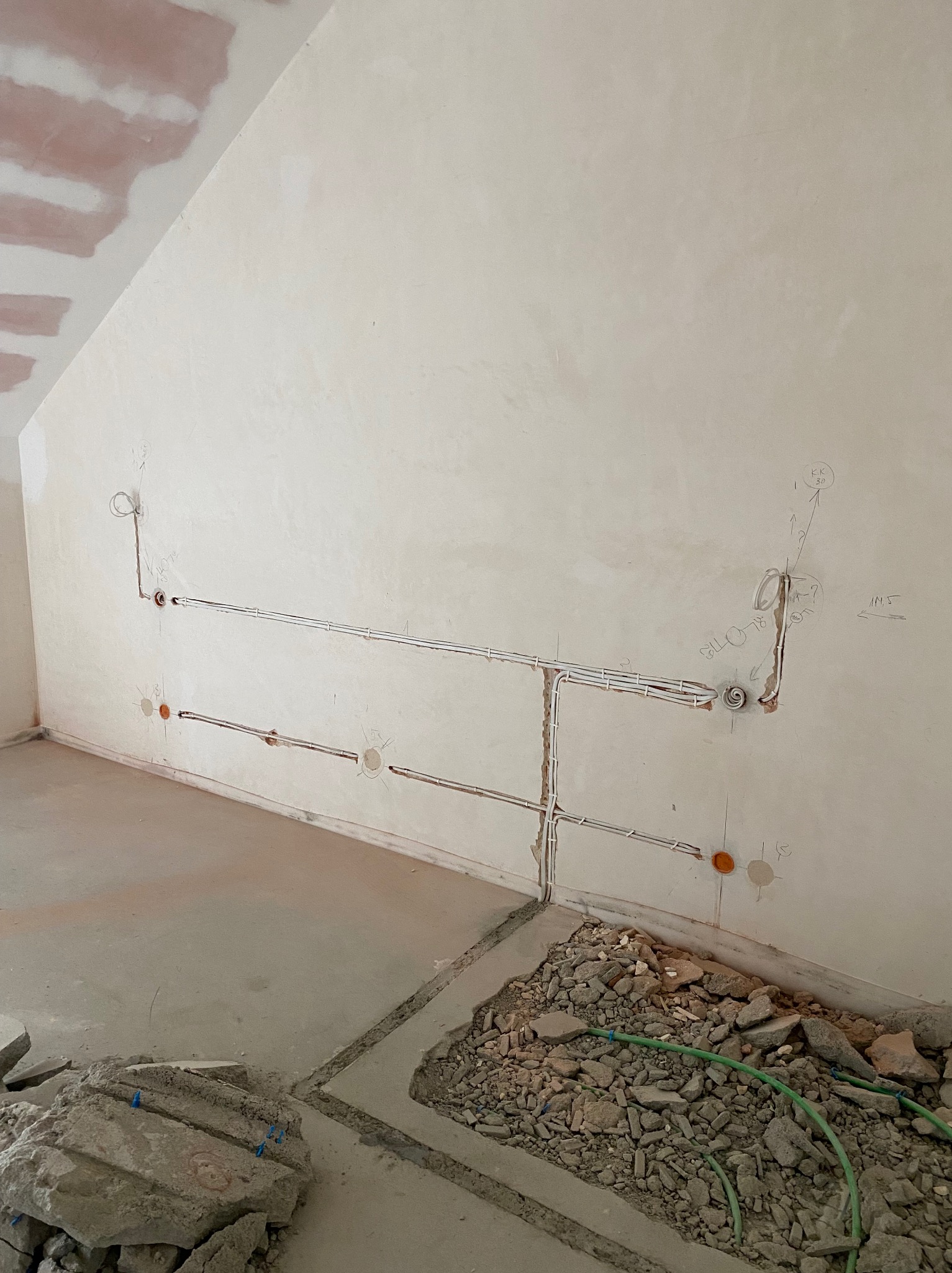 Instalacja elektryczna w trakcie realizacji we Wrocławiu: widoczne przewody w ścianie i bruzdy w podłodze, przygotowane pod wylewkę. Instalatorstwo energetyczne.