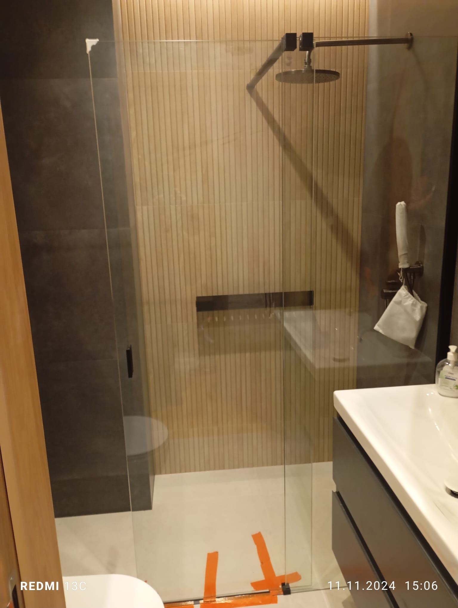 Nowoczesna kabina prysznicowa walk-in z deszczownicą i szklaną ścianką, wykończona w beżowo-szarej kolorystyce w Kiełczowie. Minimalistyczny design.