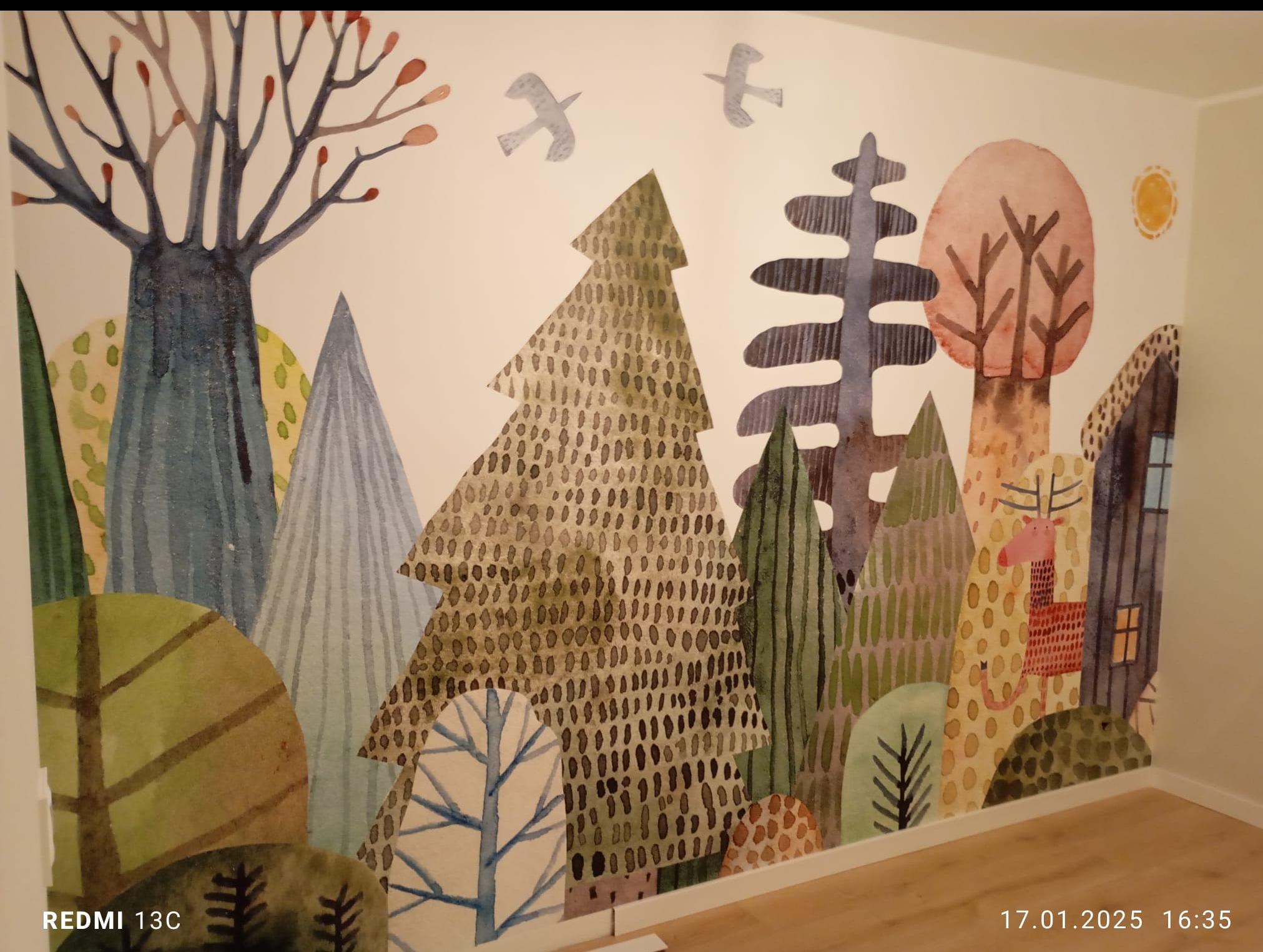 Ręcznie malowana ściana w pokoju dziecięcym z motywem leśnym: drzewa, zwierzęta i ptaki w pastelowych barwach, styl akwareli. Dekoracja wnętrza z bliska.