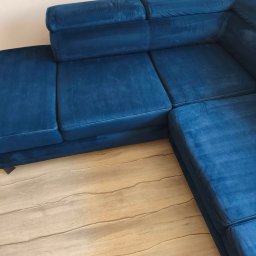 Mar-Clean - Narożnik z niebieskiego weluru na jasnej podłodze. Widoczne ślady po czyszczeniu tapicerki. Ciemniejszy odcień na siedzisku wskazuje na świeżo wyprany fragment.