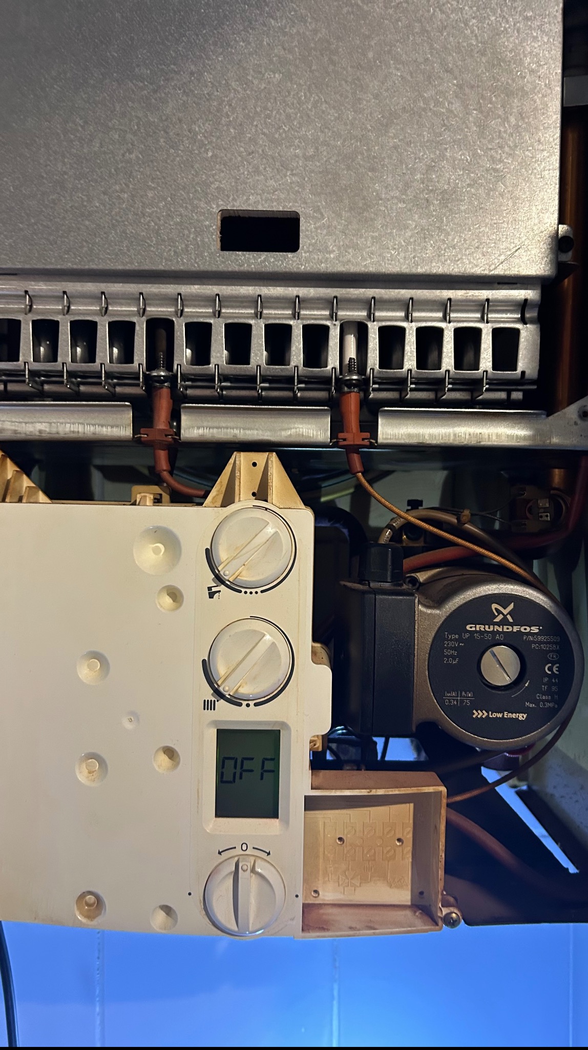 Wyłączony piec gazowy z widocznym panelem sterowania, pompą obiegową Grundfos i palnikiem. Ujęcie z bliska, detale instalacji.