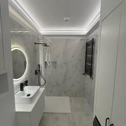 Mateusz sadecki - Nowoczesna łazienka z marmurowymi płytkami, czarną armaturą i podświetlanym lustrem. Minimalistyczny design z akcentami czerni i bieli, oświetlenie LED.