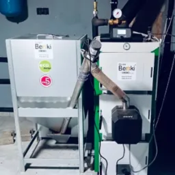 Nowoczesny, dwuczęściowy piec z podajnikiem, marki Berski Obero, z widocznym certyfikatem Eco Design i klasą 5, stojący w kotłowni.