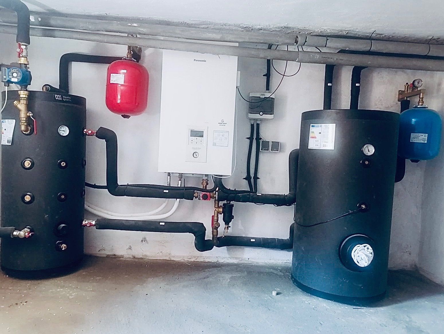 Instalacja centralnego ogrzewania z dwoma zbiornikami buforowymi, kotłem gazowym Panasonic i osprzętem hydraulicznym w kotłowni.