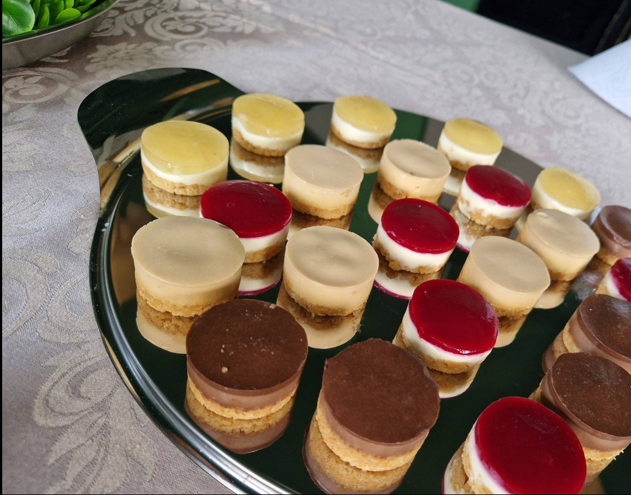 Elegancka taca z mini serniczkami o różnych smakach: cytrynowym, karmelowym, wiśniowym i czekoladowym, idealne na wykwintny catering.