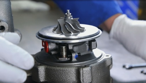 Turbosprężarka w trakcie montażu: widoczne ręce w rękawicach, narzędzia i elementy turbiny. Precyzyjna naprawa turbosprężarek w warsztacie.