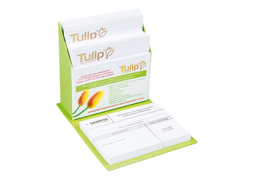 Stojak z bloczkami firmowymi Tulip dla Sandoz, z miejscem na notatki i logo, w kolorystyce biało-zielonej. Produkt reklamowy.