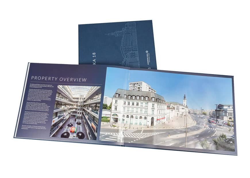 Otwarta, dwustronicowa broszura z widokiem na nowoczesne biuro i panoramą miasta. Na okładce rysunek budynku. Broszura leży na białym tle.