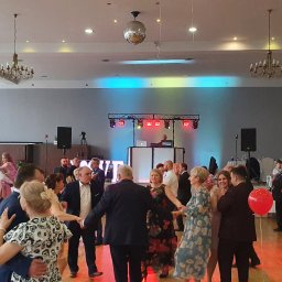 NEXT Party - Sala balowa z tańczącymi gośćmi, dekoracjami, oświetleniem scenicznym i didżejem w tle, tworząca radosną atmosferę imprezy.