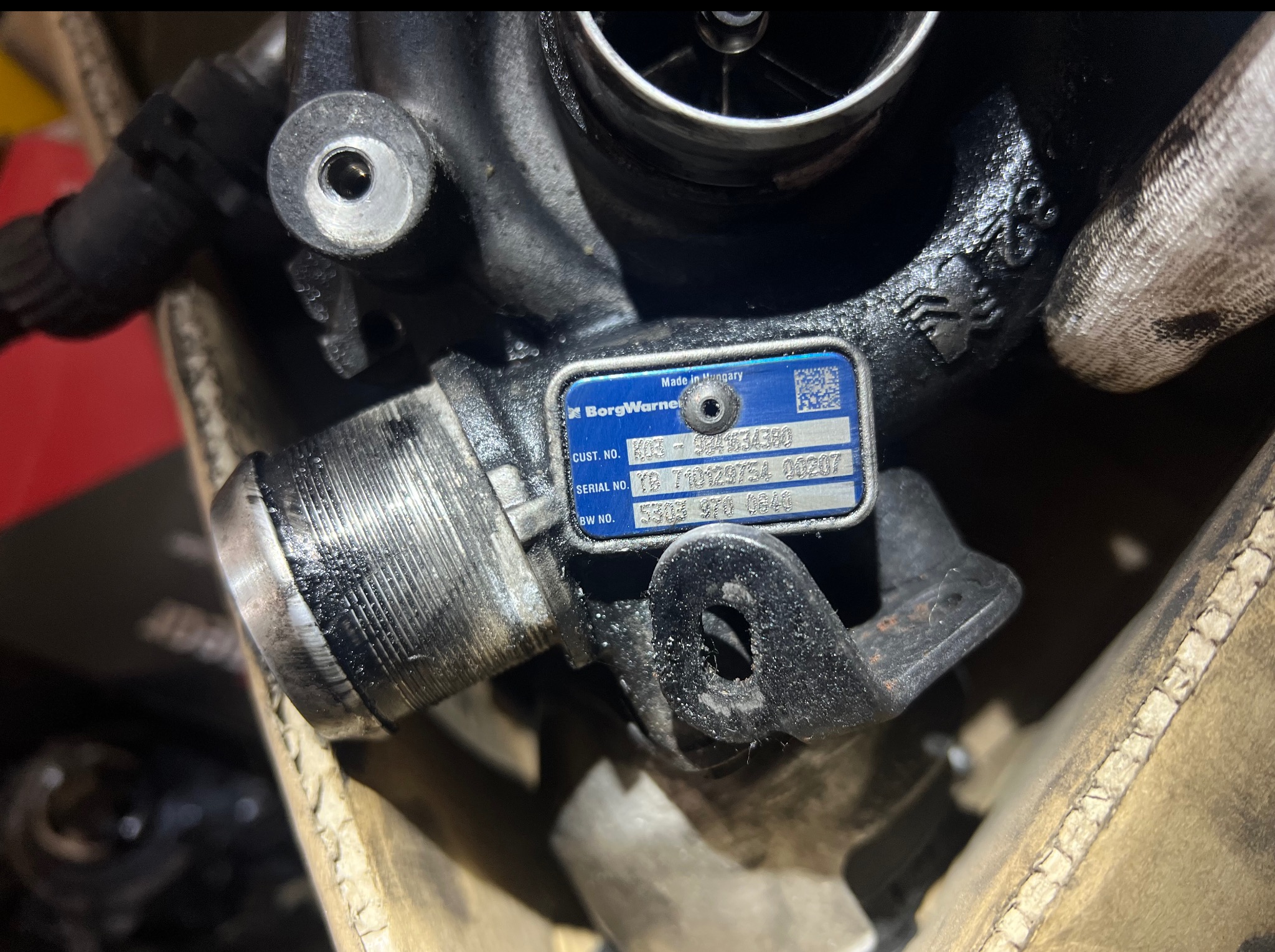 Turbosprężarka BorgWarner z tabliczką znamionową Made in Hungary, widoczna w zbliżeniu, element warsztatu samochodowego lub serwisu.