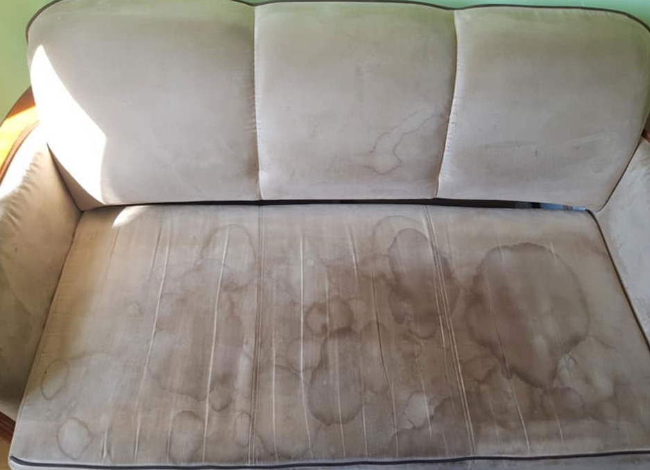 Beżowa kanapa z widocznymi plamami na siedzisku, ukazująca stopień zabrudzenia tapicerki przed czyszczeniem. Widok z góry na siedzisko i oparcie.