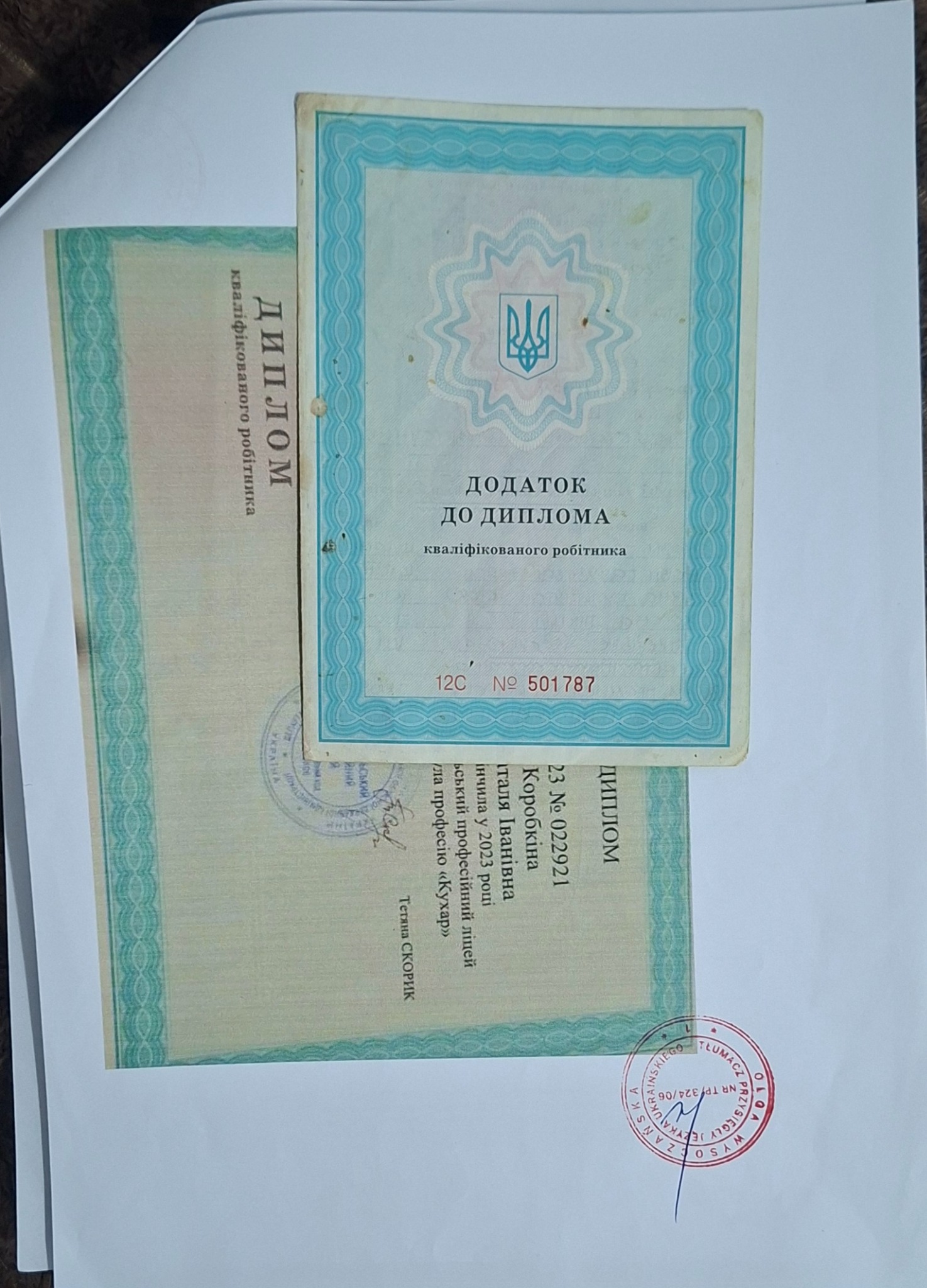 Dwa ukraińskie dyplomy zawodowe na białym tle, jeden z pieczęcią tłumacza przysięgłego. Dokumenty potwierdzające kwalifikacje zawodowe.